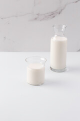 glass and jug with milk on white background