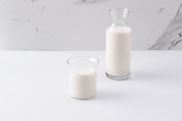 glass and jug with milk on white background
