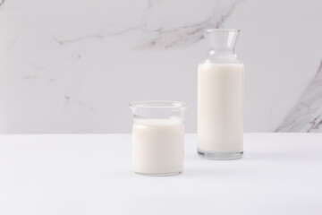 glass and jug with milk on white background