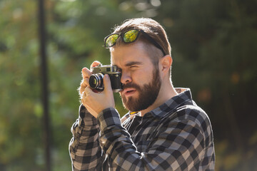 Close-up portrait man photographer taking picture with vintage camera on city green park - leisure activity and hobby concept