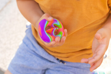 Colorful antistress sensory toy fidget push pop it in toddler's hands. Antistress trendy pop it toy. Rainbow sensory fidget. New trendy silicone toy. Snappers - obrazy, fototapety, plakaty