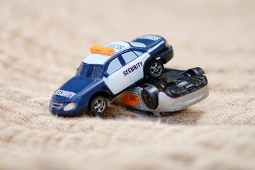 Fototapeta na wymiar A toy police car on the floor in the children s room, close-up accident. The crash of two toy cars with the inscription security, nursery