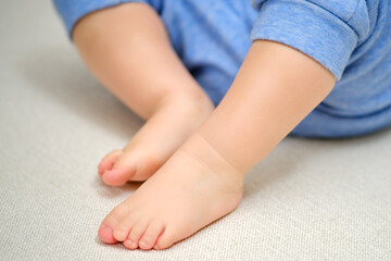 Bare feet of a child on a white warm rug, close-up. Toddler baby boy is playing lying down on the carpet in the nursery. Kid aged one year and three months