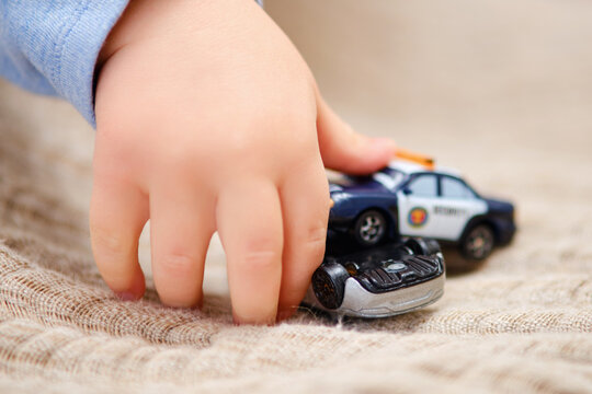 Toddler baby boy is playing with toy cars on the floor in the home room. A child plays with toys in the nursery. Kid aged one year and three months
