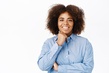 Young smiling african american woman in blue collar shirt, looking with interest and hope, listetning with joy, standing over white background