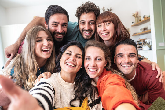 A large group of caucasian friends taking selfie sitting in living room of modern hostel