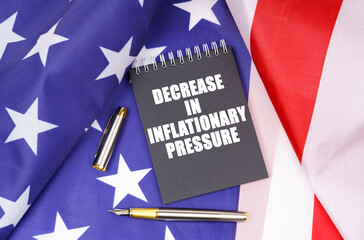 On the American flag lies a pen and a notebook with the inscription - decrease in inflationary pressure