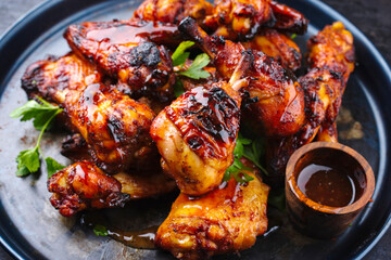 Traditionelle Hähnchenflügel und Keulen vom Grill mit scharfer Chili Mango Sauce und Koriander serviert als close-up auf einem rustikalen Board