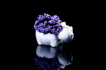 ceramic vase in the form of a dog with flowers with reflection, black background isolated,