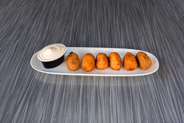 ham croquettes with sauce over a white plate