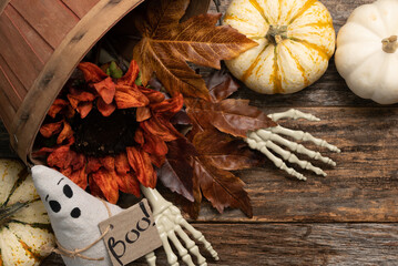 Halloween background concept on barnwood with autumn leaves, pumpkin, skeleton hands and a cloth...