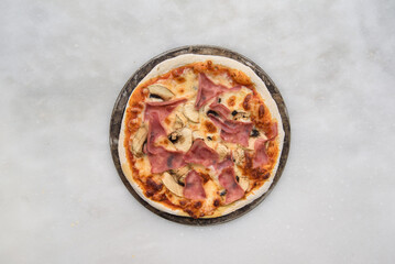pizza prosciutto e funghi top view on a white stone