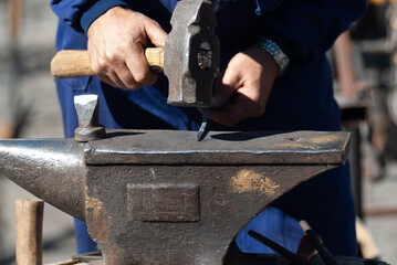 Blacksmith hammering on a metal anvil