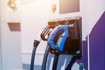 Hand plugging in a charger in an electric car socket.Electric car or ev is charging at station