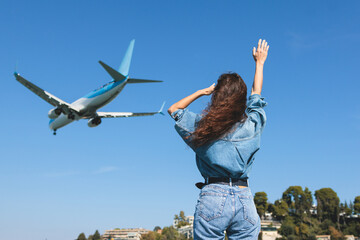 Girl and airplane in flight, landscape with woman standing with hands raised up, waving arms and...