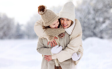 Fototapeta na wymiar Happy mother embracing little girl daughter while having fun in snowy weather outdoor