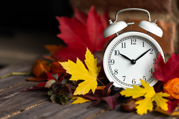 Fall winter time change concept. Autumn composition with retro alarm clock, bright yellow and red...