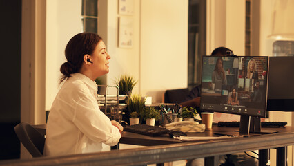 Office worker using videocall meeting on computer to talk to people on webcam, having remote conversation on internet teleconference. Attending online videoconference call at sunset.