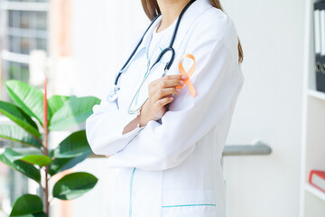 Doctor holding and showing orange awareness ribbon in her hands