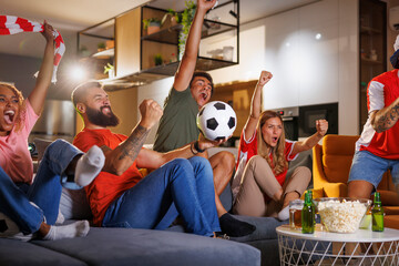 Football fans cheering while watching the game on TV at home