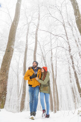 Fototapeta na wymiar Couple taking a walk on snowy winter day in the forest