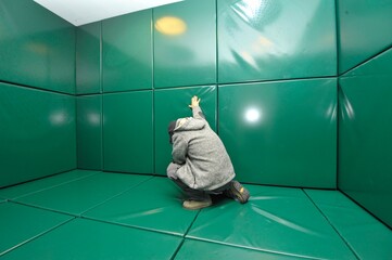Man kneeling in green padded cell