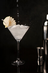 Pear cider in martini glass with cut pear garnish on black background. Close up