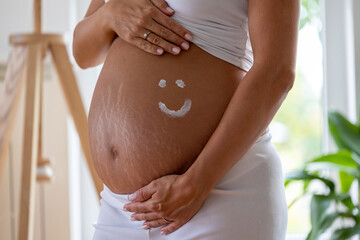 Smiley drawn with cream on pregnant belly - obrazy, fototapety, plakaty