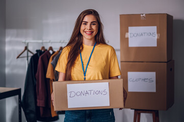 Portrait of a volunteer holding cardboard box with his colleagues in the background