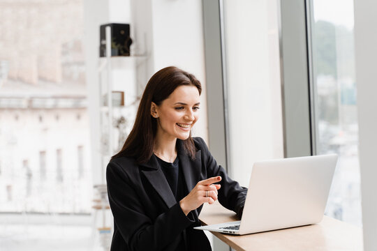 Online video meeting with colleagues and business partners. Team discussion and problem solving remotely. Girl manager with laptop gesticulates, discuss trends and tasks in white office.
