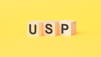 usp - text on wooden cubes, on yellow background. unique selling proposition concept