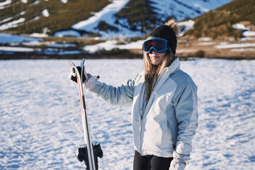 stylish pretty girl waits on the mountain with her skis