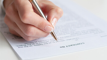 Close shot of a woman hand writing something on the paper on the foreground