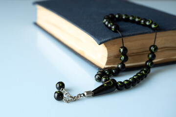 Holy Quran with beads over white background closeup. Muslim faith concept