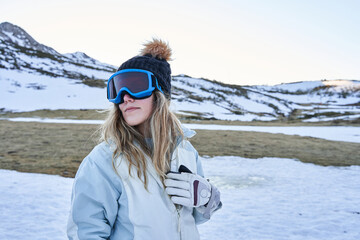 beautiful girl poses before the camera with a casual and calm appearance equipped with a hat and snow goggles