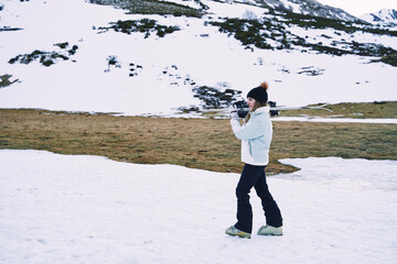 pretty girl carries ski equipment on her shoulder while moving down the mountain