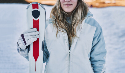 Closed shot of a pretty girl holding some skis in front of the camera.
