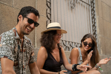 a group of three friends having fun and laughing on a bench in the street