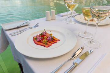 Fish filet on a plate served on a restaurant table with wine