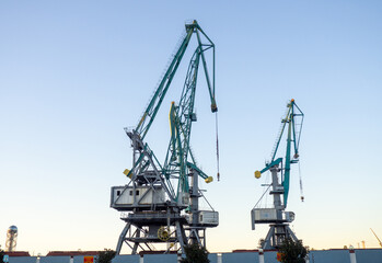 Fototapeta na wymiar Port cranes against the sky. loading mechanism. Sea freight concept