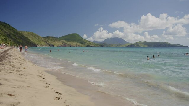 Distant people swimming in waves at ocean beach / Basseterre, St. Kitts