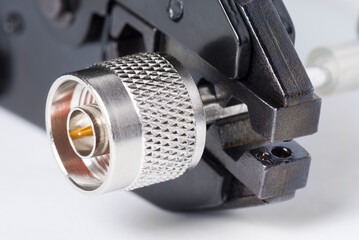 Crimping tool with N male type coaxial connector and cable.  High frequency connector used in radio wave systems, high frequency transmitters and communication systems.