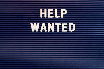 Pushboard sign that says help wanted in plastic letters