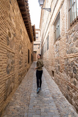 Fototapeta na wymiar Young woman traveller walking through a narrow street during a antumn afternoon.
