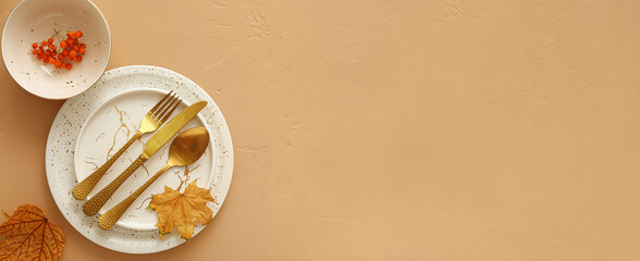 Autumn table setting with fallen leaves and rowan on beige background with space for text
