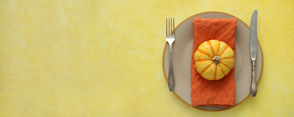 Autumn table setting with fresh pumpkin on yellow background with space for text