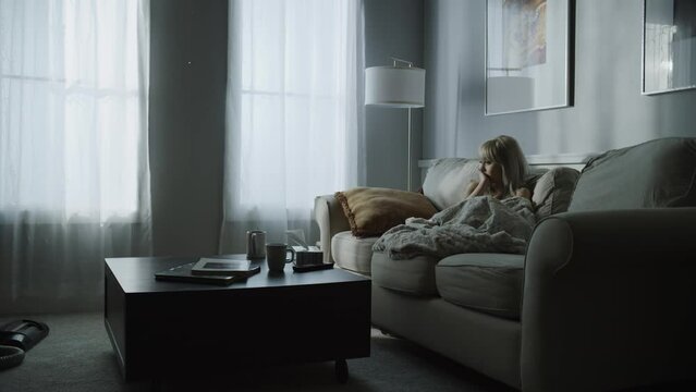 Distant woman sitting on sofa watching television / Cedar Hills, Utah, United States