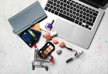 Laptop, wallet, credit cards, cosmetics and shopping cart on light background