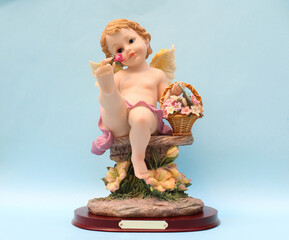 Estatuilla de Ángel sosteniendo una canasta con flores. 