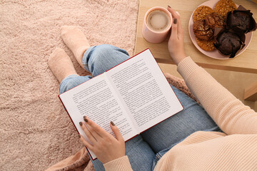 Woman with cup of coffee reading book at home